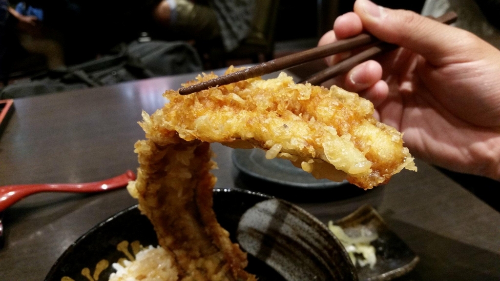 浅草『天丼秋光』の五代目天丼に乗っている、穴子の天ぷらを箸で持ち上げた写真