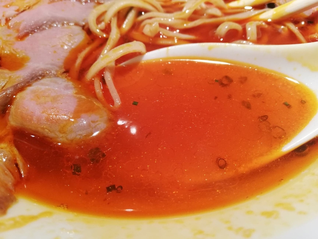 上野『さんじ』の赤潮ラーメンのスープを、レンゲですくった写真