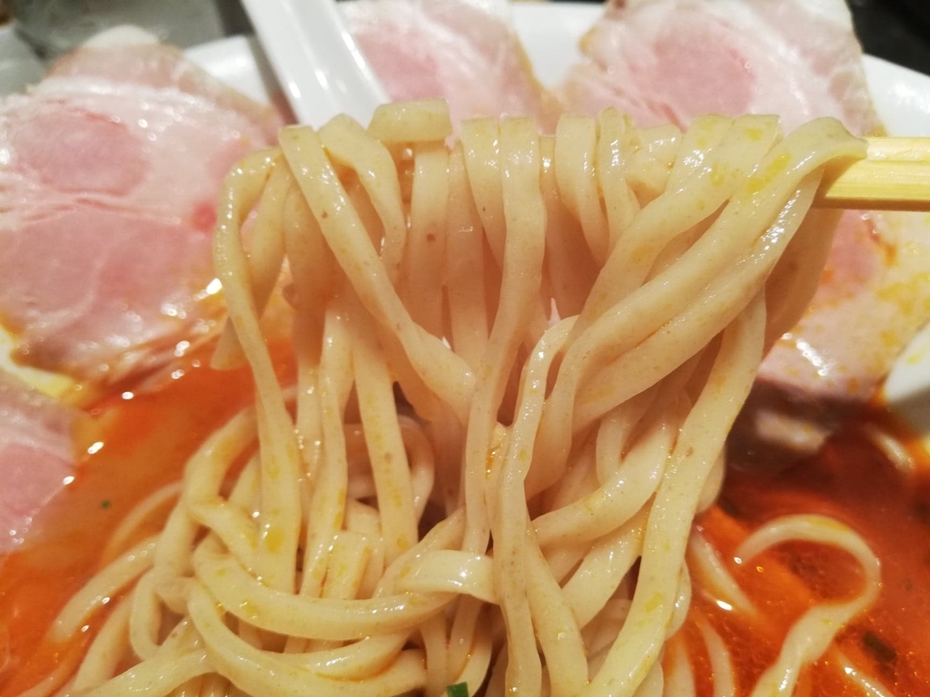 上野『さんじ』の赤潮ラーメンの麺を、箸で掴んでいる写真