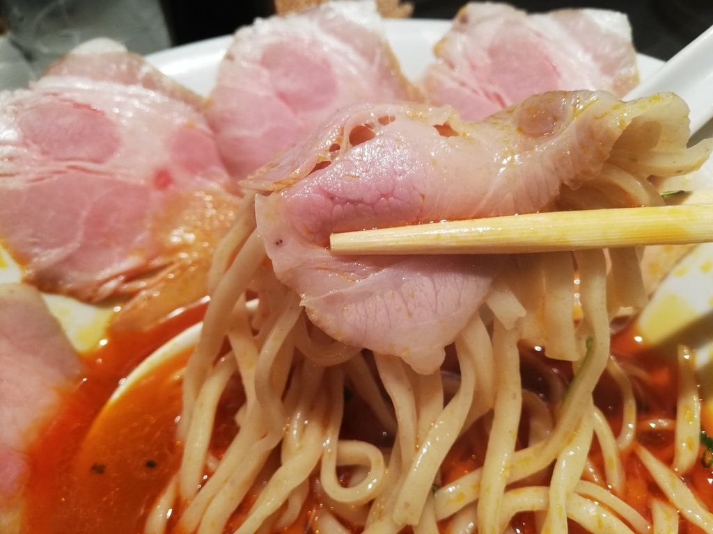 上野『さんじ』の赤潮ラーメンの麺とチャーシューを、箸で掴んでいる写真
