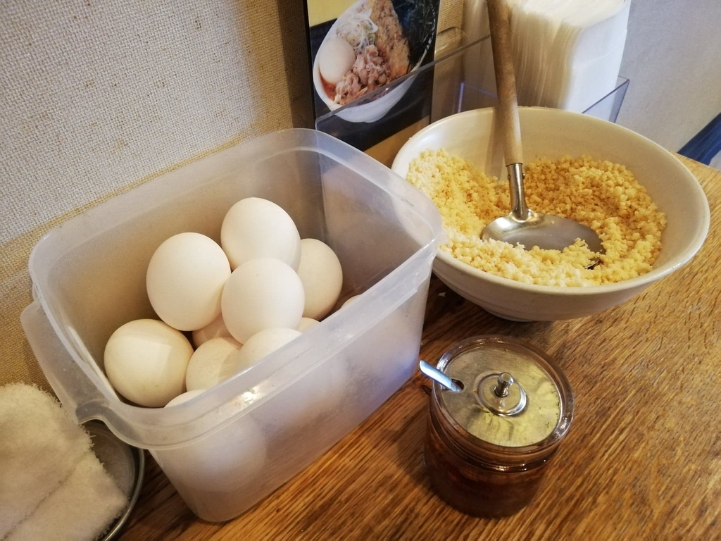 なぜ蕎麦にラー油を入れるのか。（池袋の壬生）の卓上の生卵と天かす