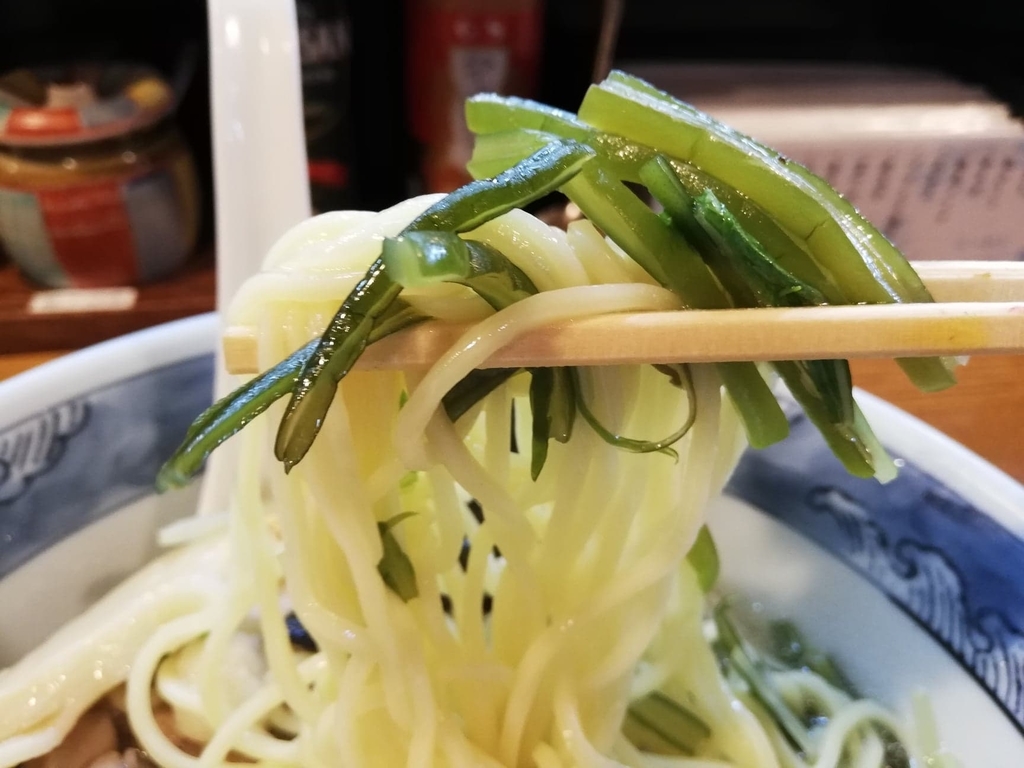 箸で掴んだ特選塩ラーメンの麺と茎わかめ