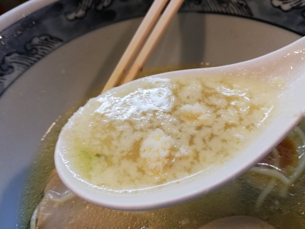 レンゲですくった特選塩ラーメンのスープと粉チーズ