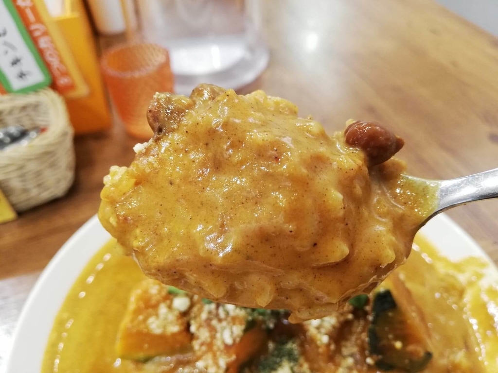 スプーンですくったヤミツキカリー西池袋店のホクホクかぼちゃのチーズカリー特盛の豆とカレーライス