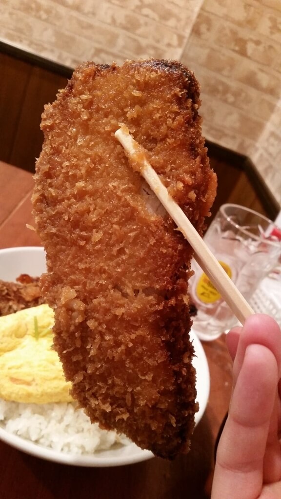 箸で掴んだ、炉端バルさま田のとろとろ玉子の角煮かつ丼ダブル大盛りの角煮かつ