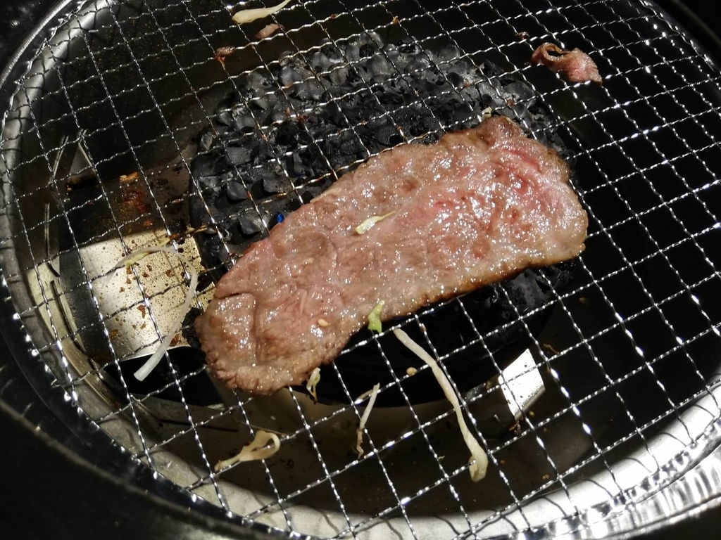 浅草焼肉たん鬼『鬼く丼』のお肉を網で焼いている写真