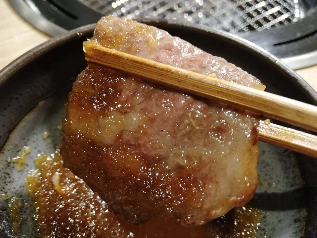 浅草焼肉たん鬼『鬼く丼』のお肉におろしを付けて箸で掴んだ写真