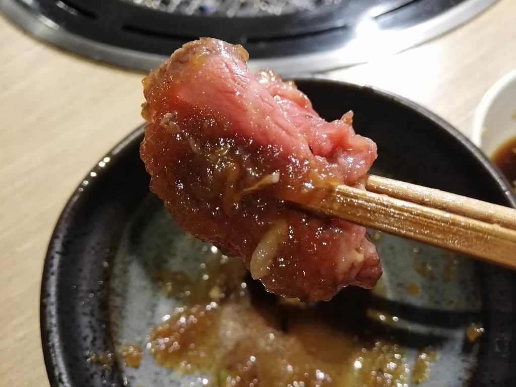 浅草焼肉たん鬼『鬼く丼』の、焼いてないお肉におろしを付けて箸で掴んだ写真