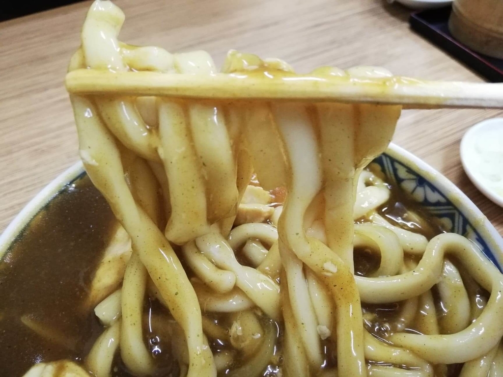 浅草『翁そば』のカレー南蛮うどんの麺を箸で掴んだ写真