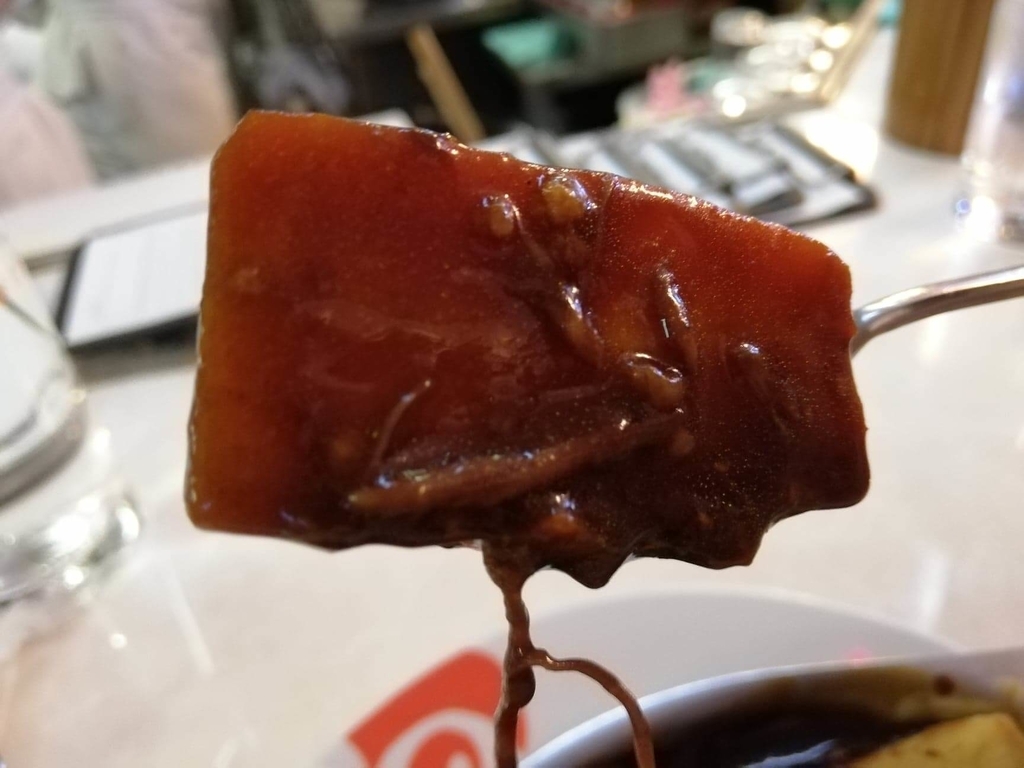 浅草『洋食屋ヨシカミ』のビーフシチューの中にあるニンジンを、スプーンで持ち上げた写真