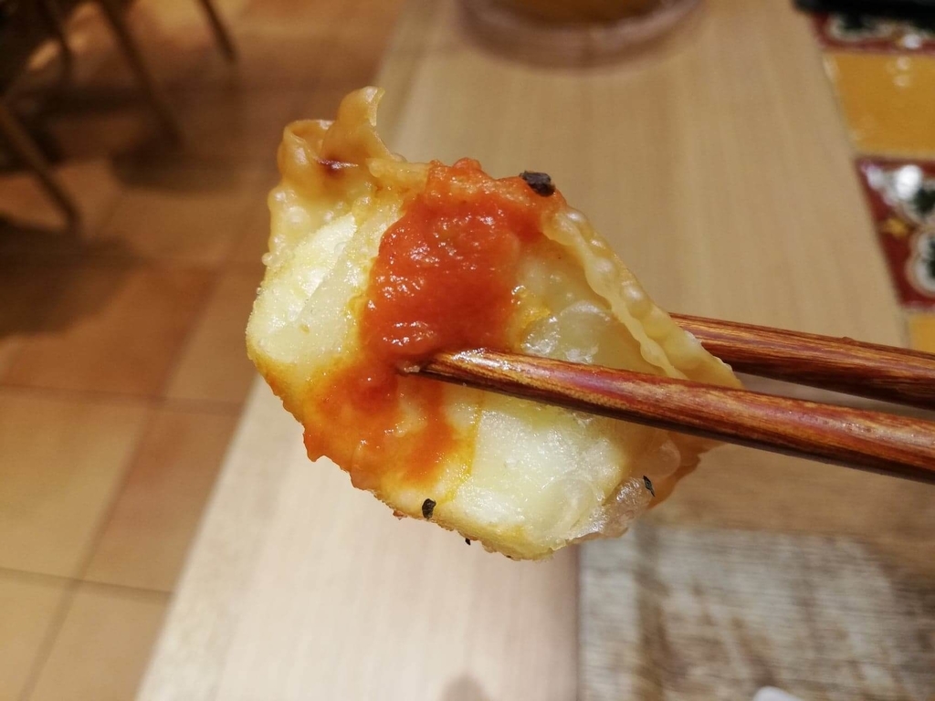 新宿ミロード店『太陽のトマト麺withチーズ』の、チーズ揚げ餃子を箸で持ち上げた写真