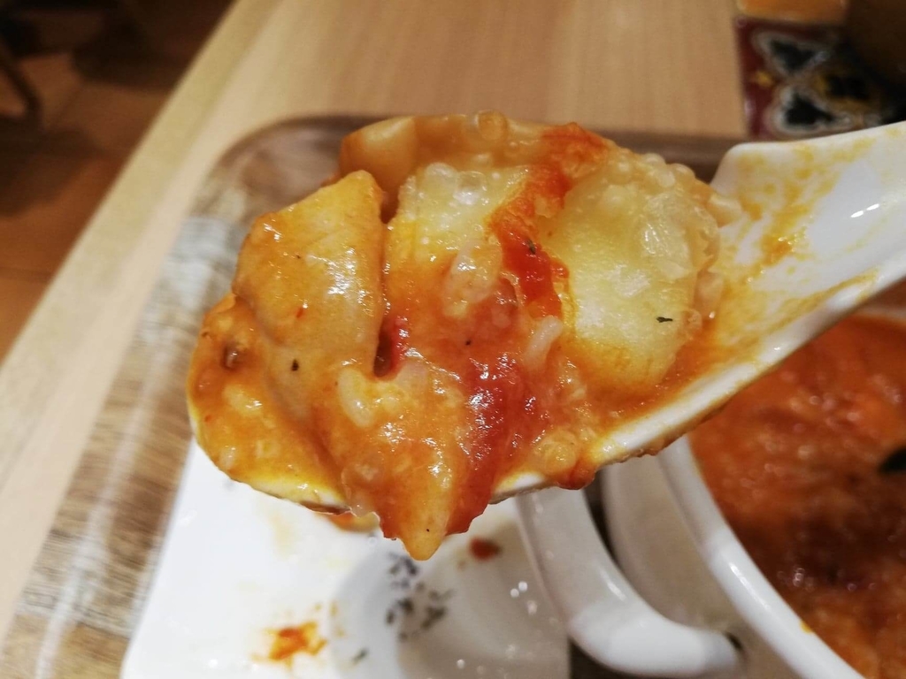 新宿ミロード店『太陽のトマト麺withチーズ』の、チーズ揚げ餃子とスープをレンゲですくっている写真