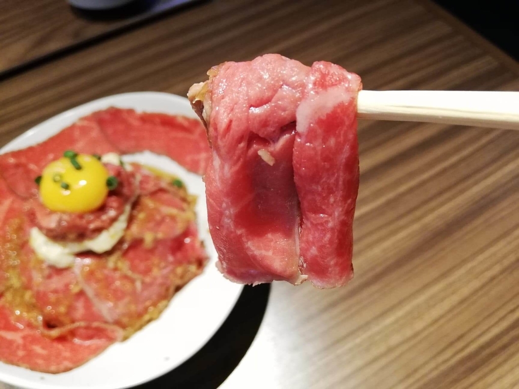 新宿『焼肉ブルズ』の特選和牛のローストビーフ丼のお肉を箸で掴んだ写真