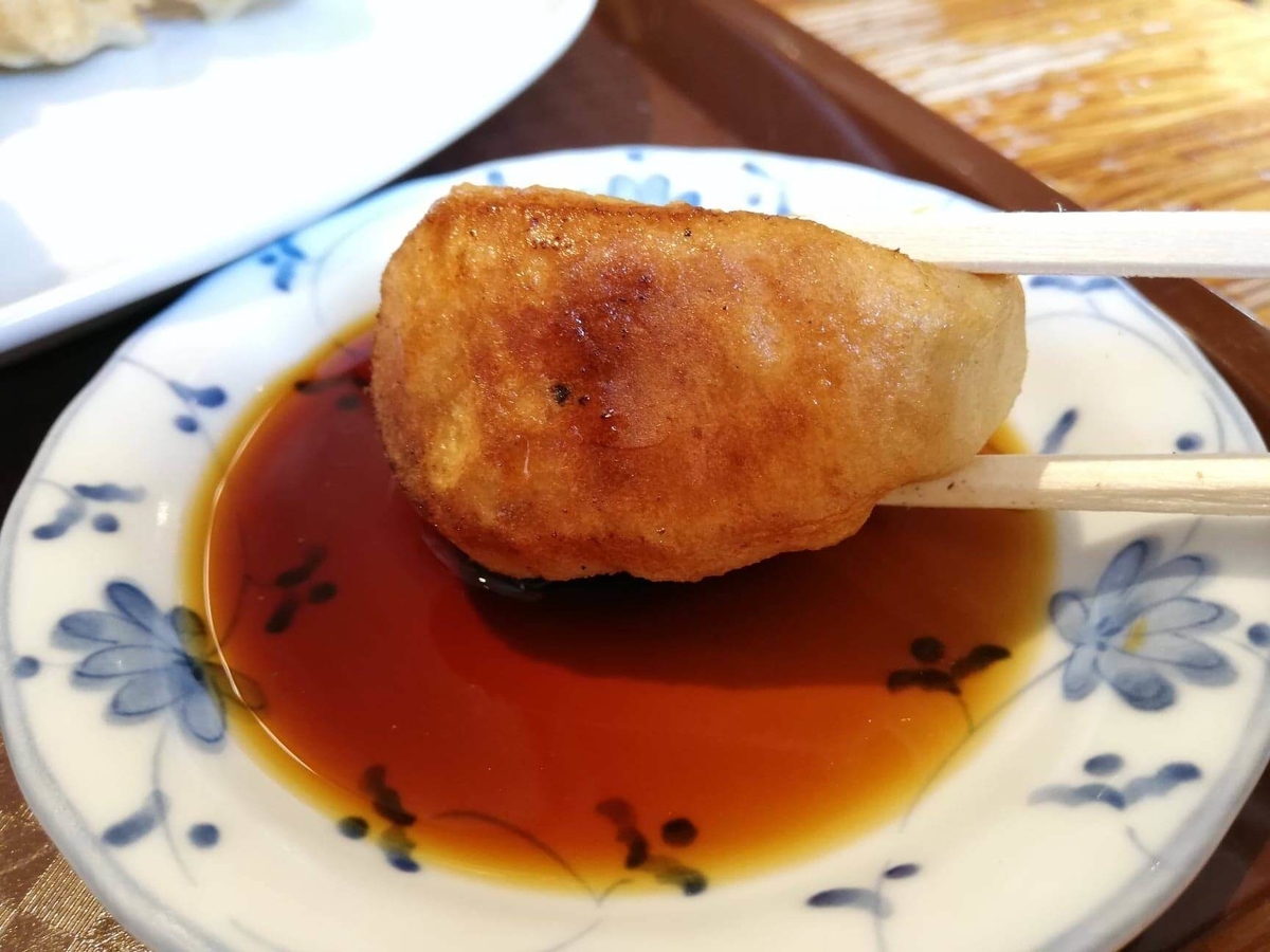 亀有『ホワイト餃子』の焼き餃子を、醤油タレにつけている写真