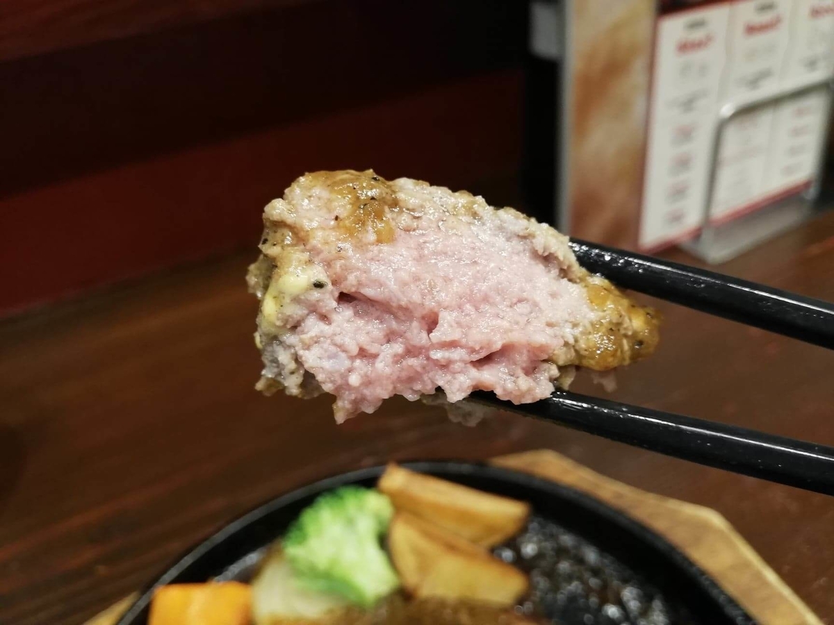 池袋『札幌牛亭』の、平日ランチタイム限定ハンバーグステーキセットのハンバーグを箸で掴んでいる写真