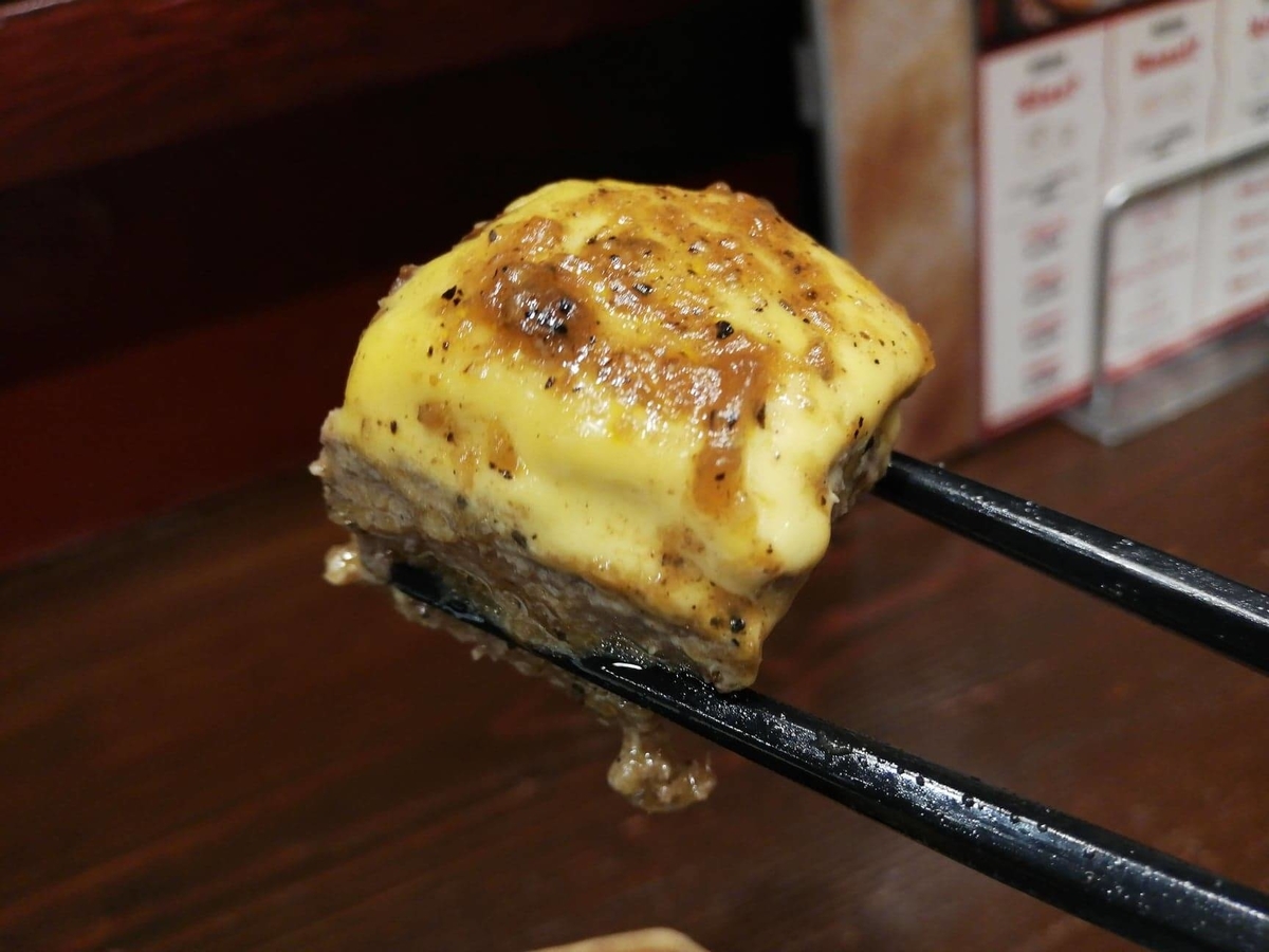 池袋『札幌牛亭』の、平日ランチタイム限定ハンバーグステーキセットのハンバーグを、チーズと一緒に箸で掴んでいる写真