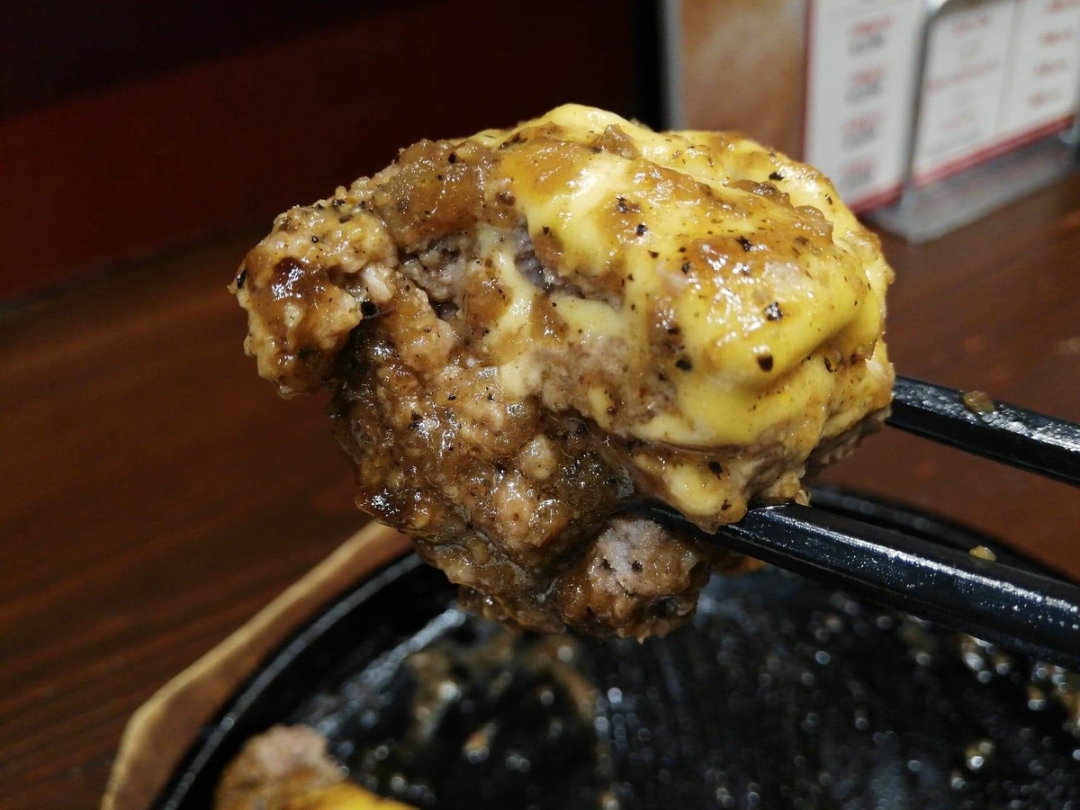 池袋『札幌牛亭』の、平日ランチタイム限定ハンバーグステーキセットのハンバーグを、チーズと一緒に箸で掴んでいる写真