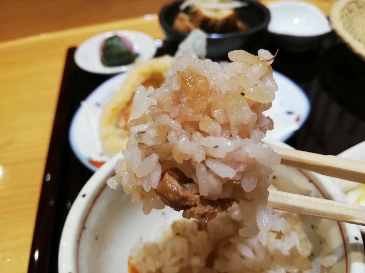 稲田堤『石づか』の炊き込みご飯を箸で掴んでいる写真