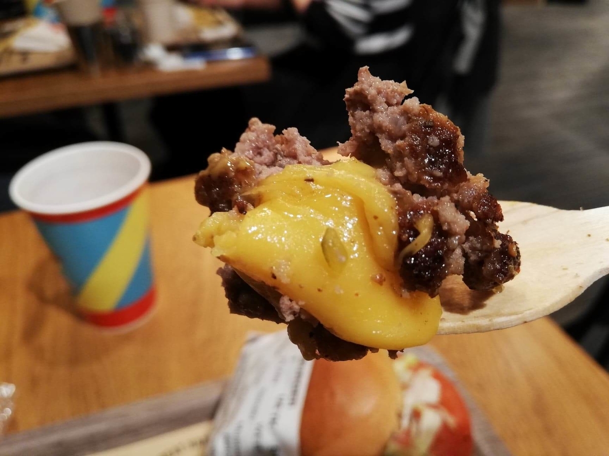 渋谷『ファットバーガー（FATBURGER）』のUSキングバーガーのパティとチーズを、フォークですくっている写真