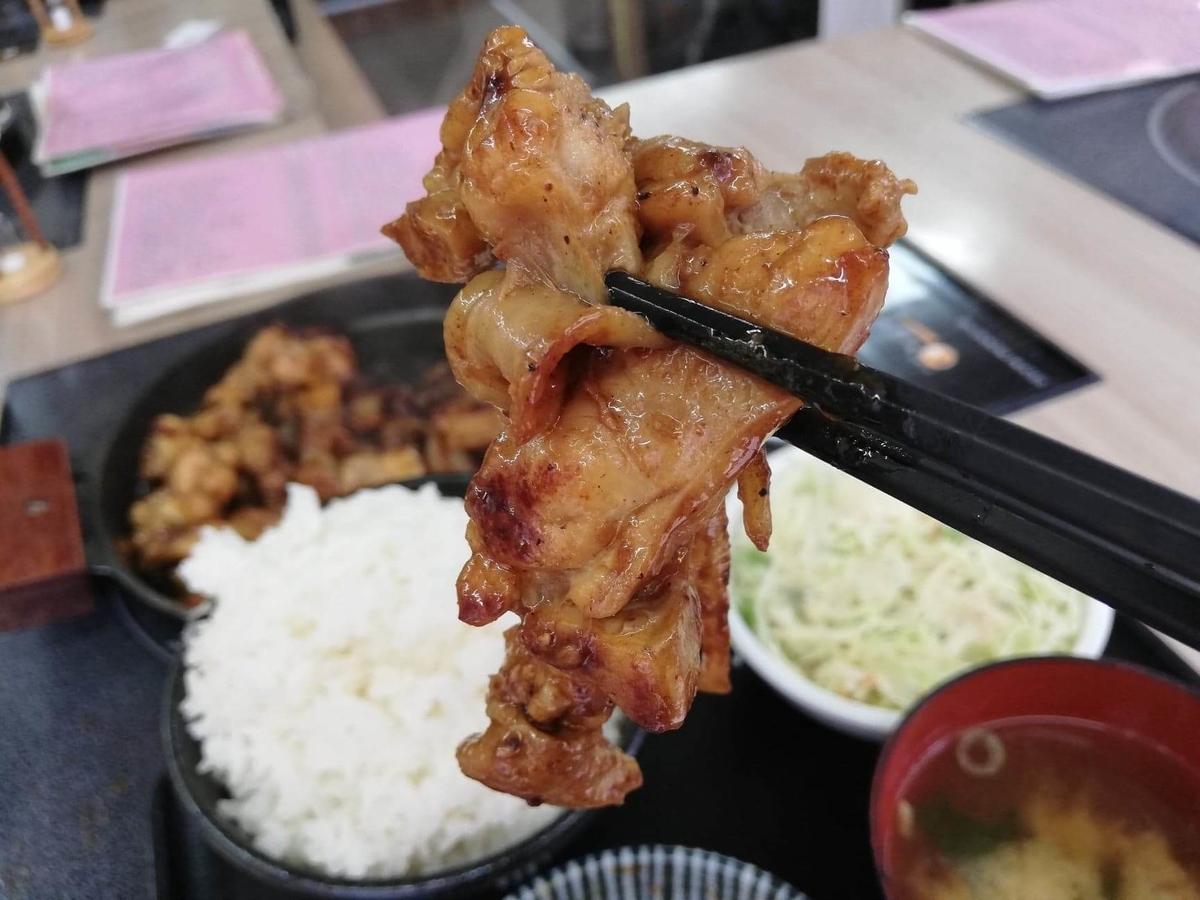 江古田『ふくふく食堂』のBBQ定食の肉を箸で掴んでいる写真