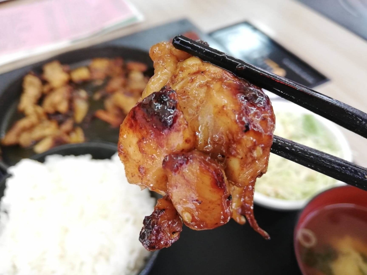 江古田『ふくふく食堂』のBBQ定食の肉を箸で掴んでいる写真