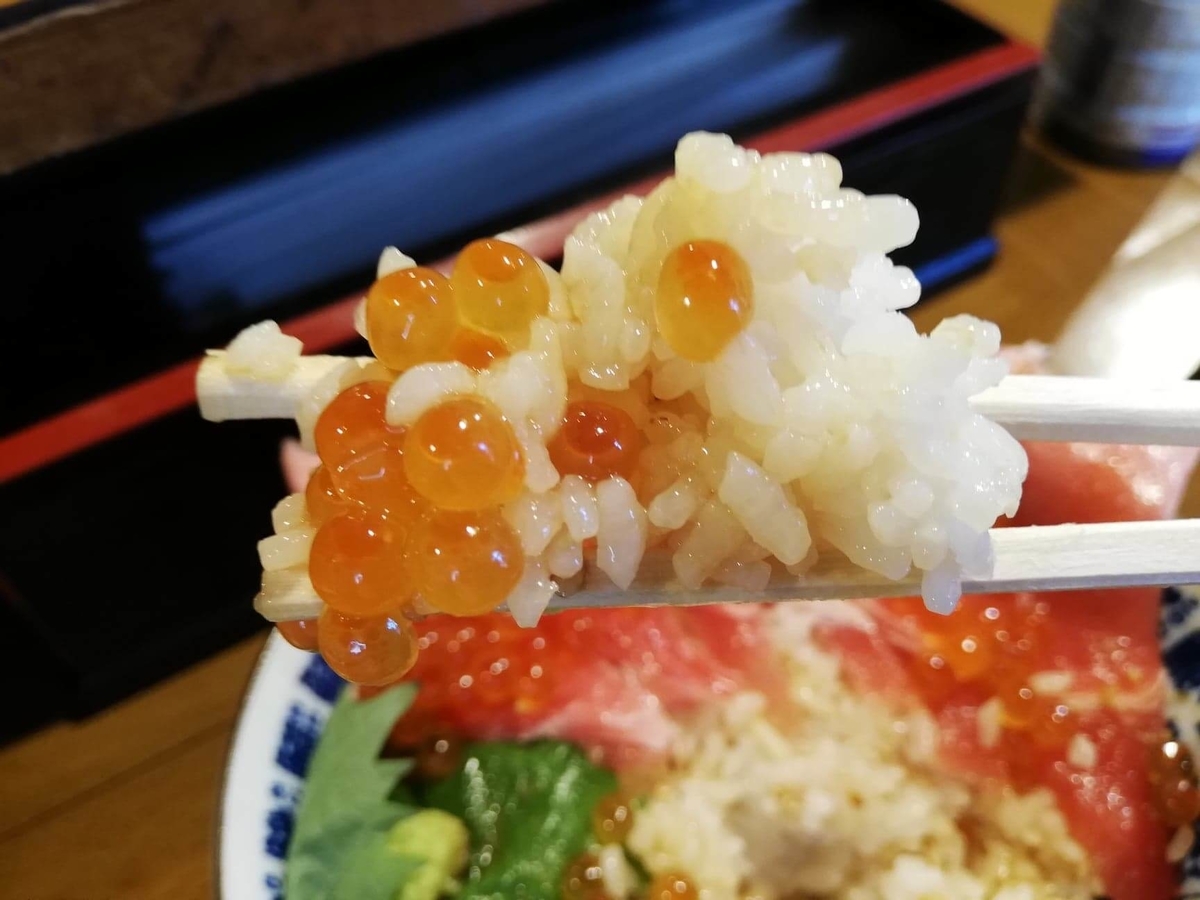 立川『モンロー』の天然本まぐろ中とろマシマシいくらマシマシ海鮮丼のイクラを、箸で掴んでいる写真