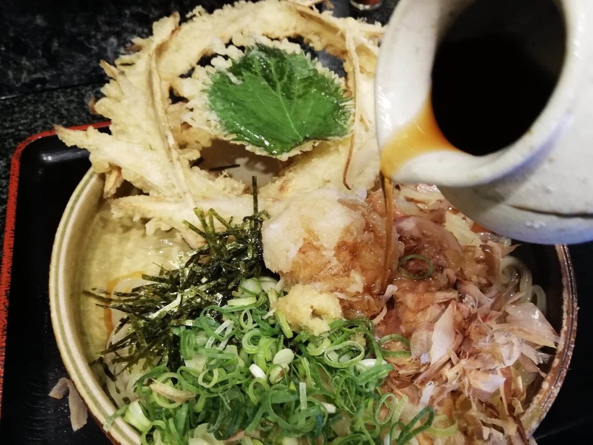 高田馬場『大地のうどん』のごぼうおろしぶっかけにタレを入れている写真