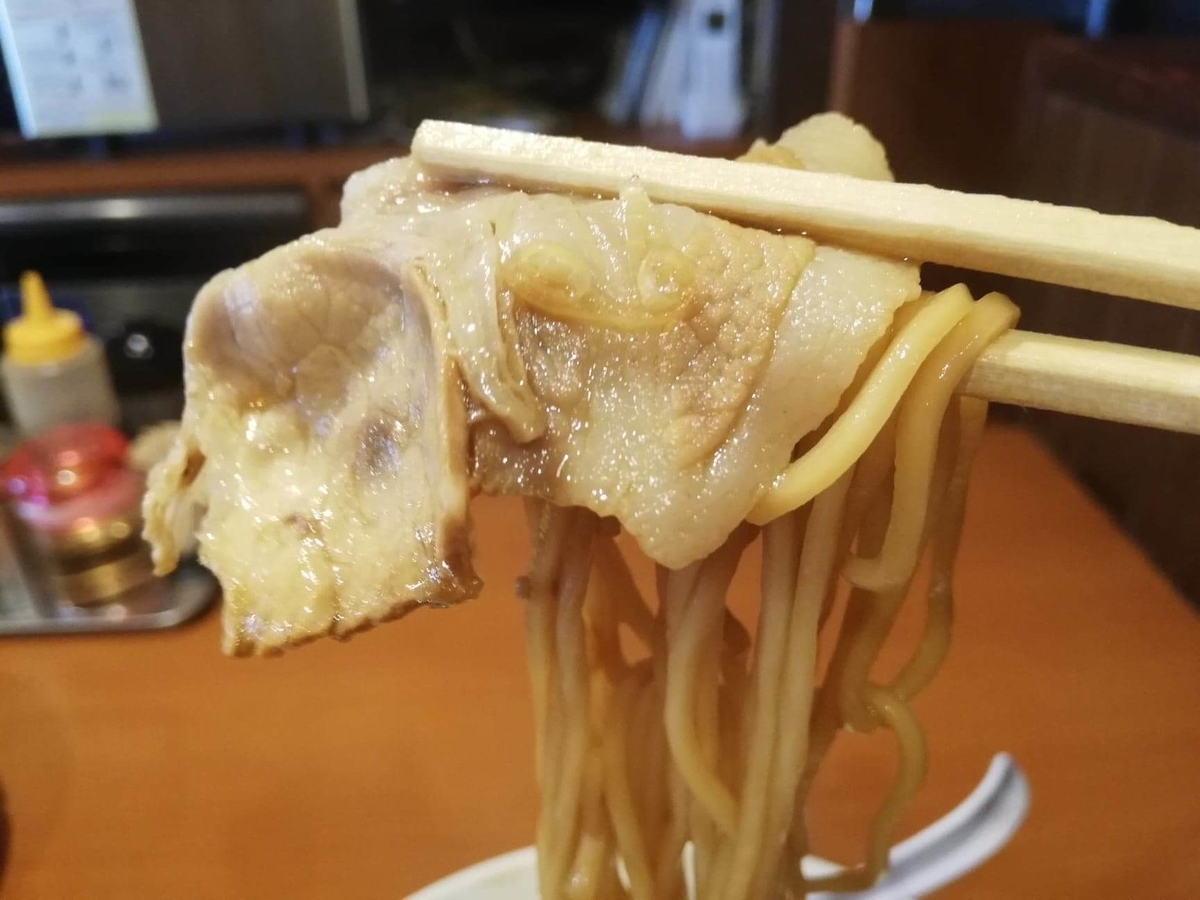 『末廣ラーメン本舗』高田馬場分店のチャーシュー麺を箸で掴んでいる写真
