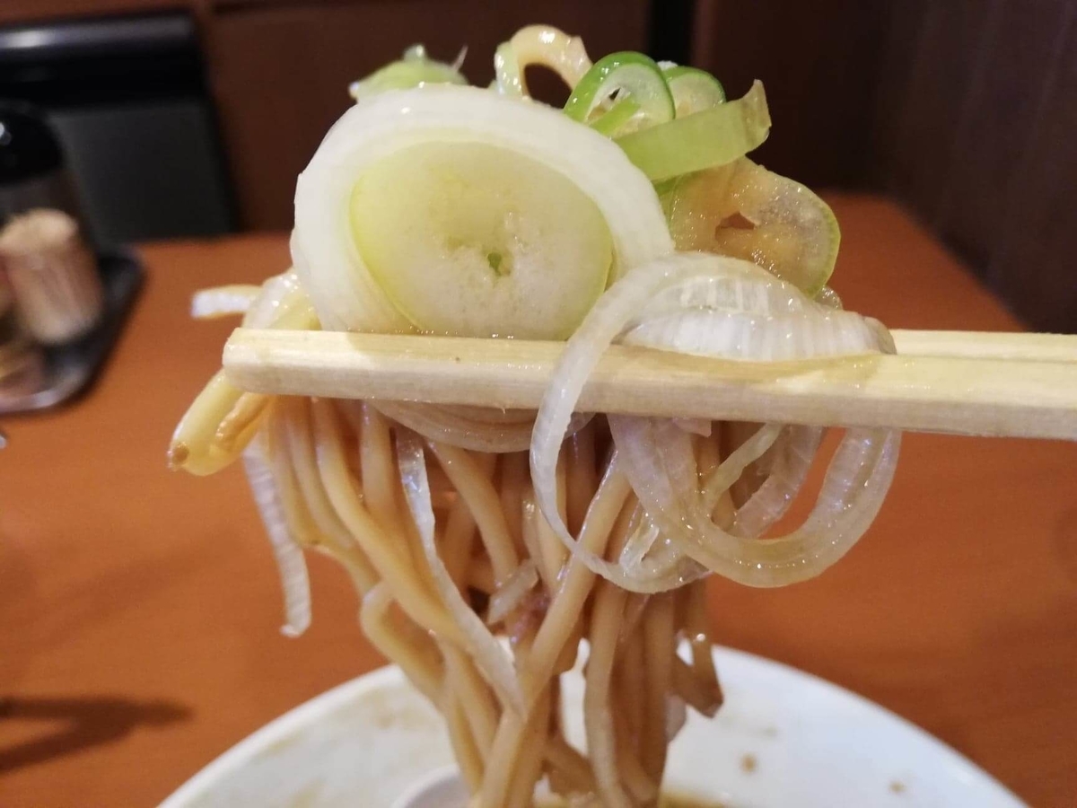 『末廣ラーメン本舗』高田馬場分店の麺とネギを箸で掴んでいる写真