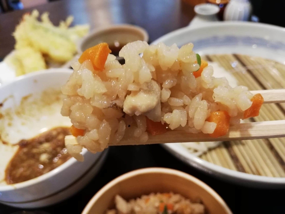 稲庭うどん『佐藤養助』秋田店の比内地鶏ご飯を箸で掴んでいる写真