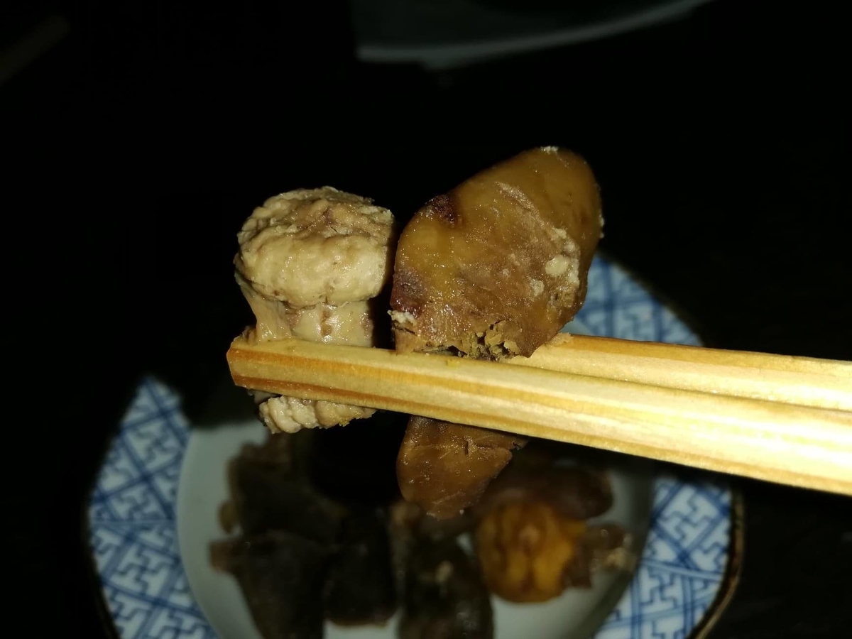 『秋田きりたんぽ屋大町分店』の比内地鶏とりモツ煮を、箸で持ち上げた写真
