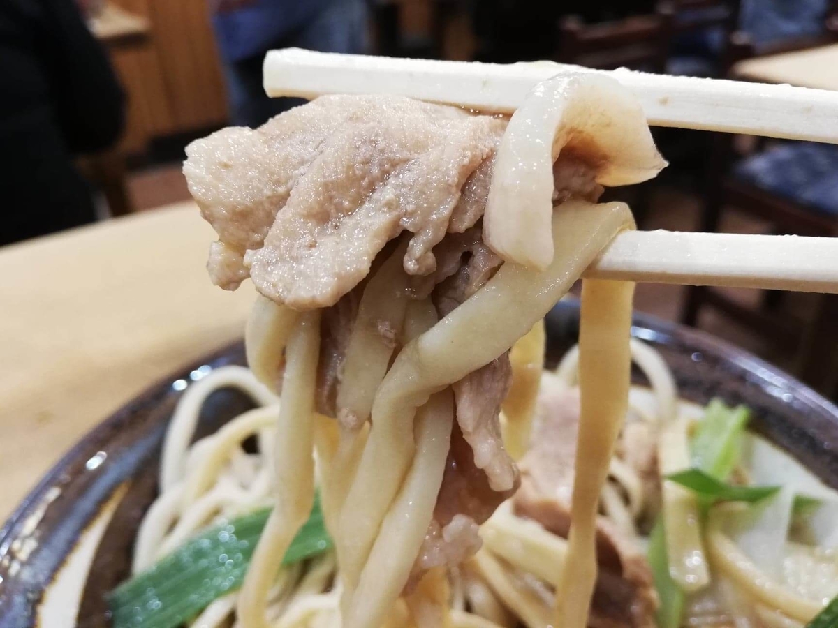 『浅草角萬』の麺と肉南蛮を箸で持ち上げている写真