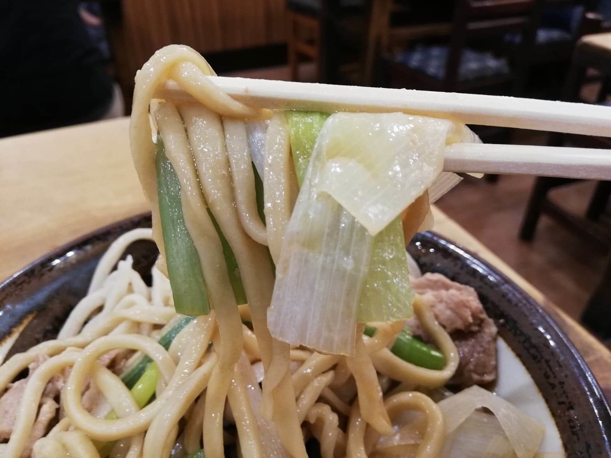 『浅草角萬』の麺とネギを箸で持ち上げている写真