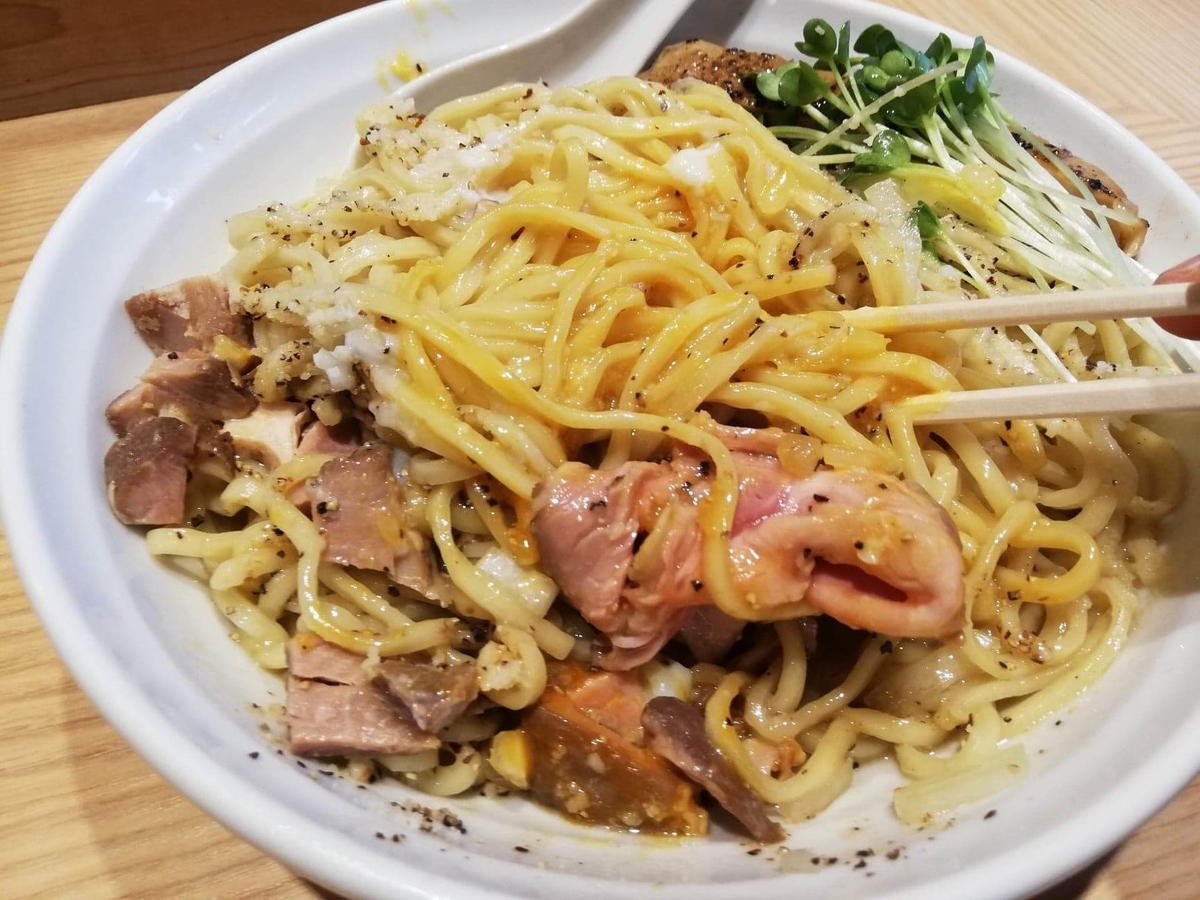 秋津(新秋津)『麺場二寅』の鶏ボナーラを混ぜている写真
