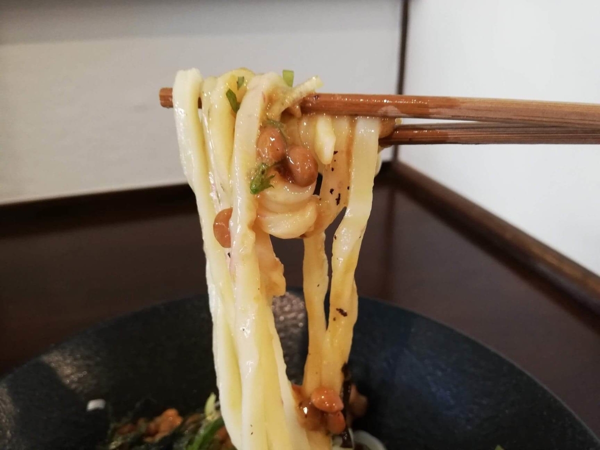 川越『創作うどん専門店くらうど』の、３種のしその納豆おろしうどんの麺を箸で持ち上げている写真