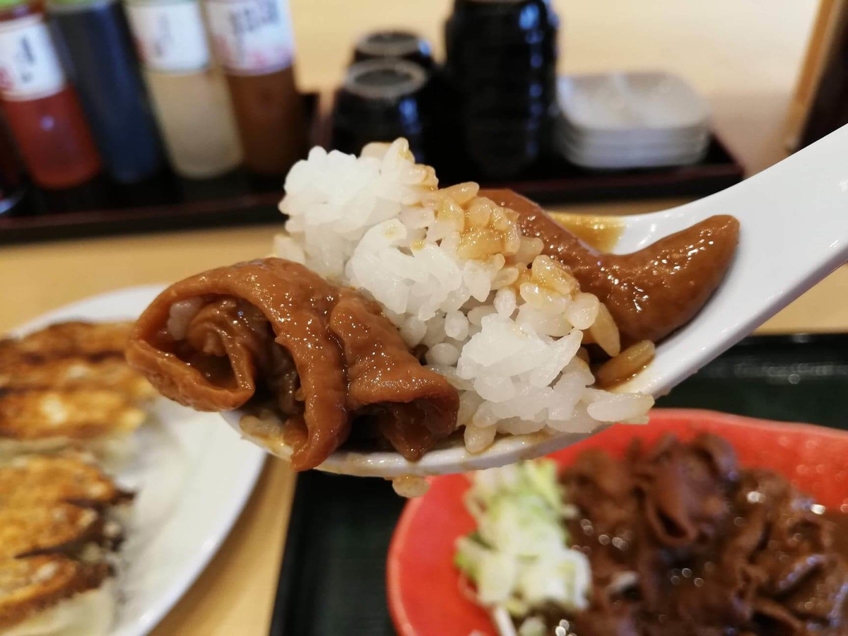 久米川『東京餃子食堂』のモツ煮をレンゲですくっている写真