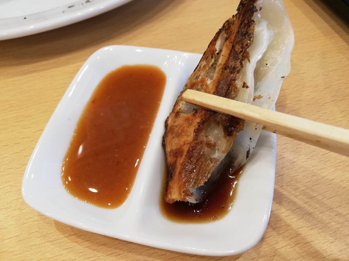 久米川『東京餃子食堂』の餃子をタレにつけている写真