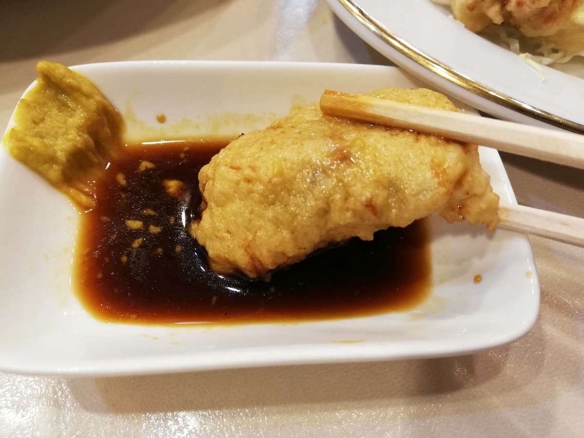 香川県高松市『洋食おなじみ』のとりの骨抜きを、カラシ醤油につけている写真