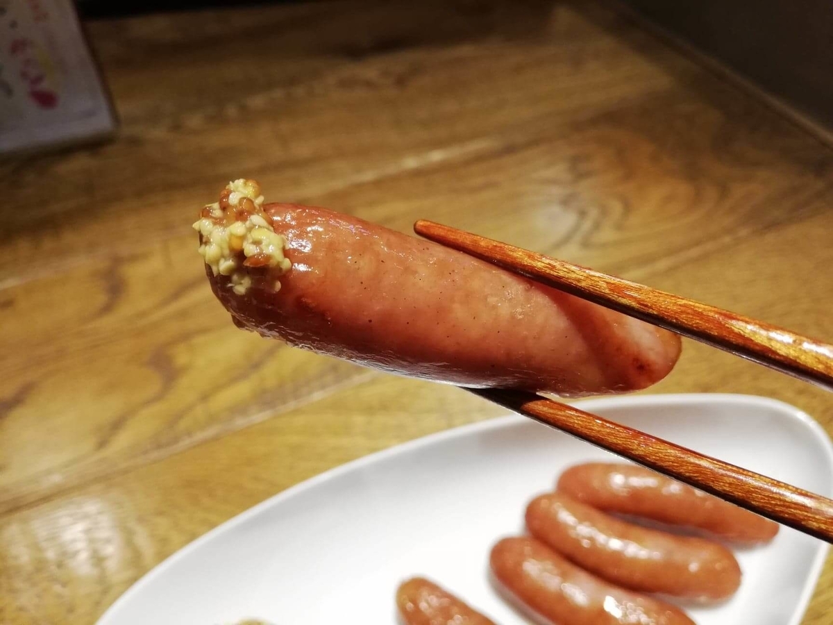 香川県高松市『瀬戸内豚料理紅い豚』の宮殿ソーセージを箸で掴んでいる写真