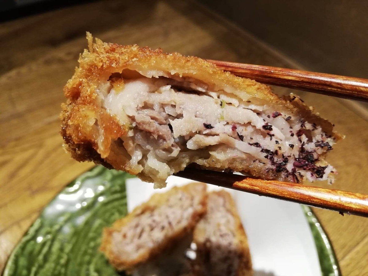 香川県高松市『瀬戸内豚料理紅い豚』の梅しそロールカツを箸で掴んでいる写真