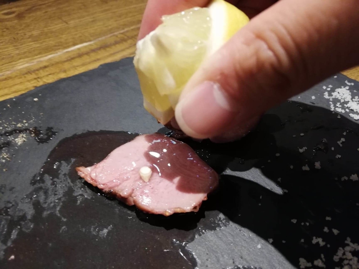 香川県高松市『瀬戸内豚料理紅い豚』の豚タンにレモンをかけている写真
