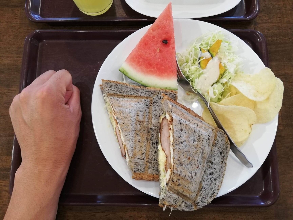 香川県高松市『三びきの子ぶた』の、テリヤキチキンチーズサンドウィッチと拳のサイズ比較写真 