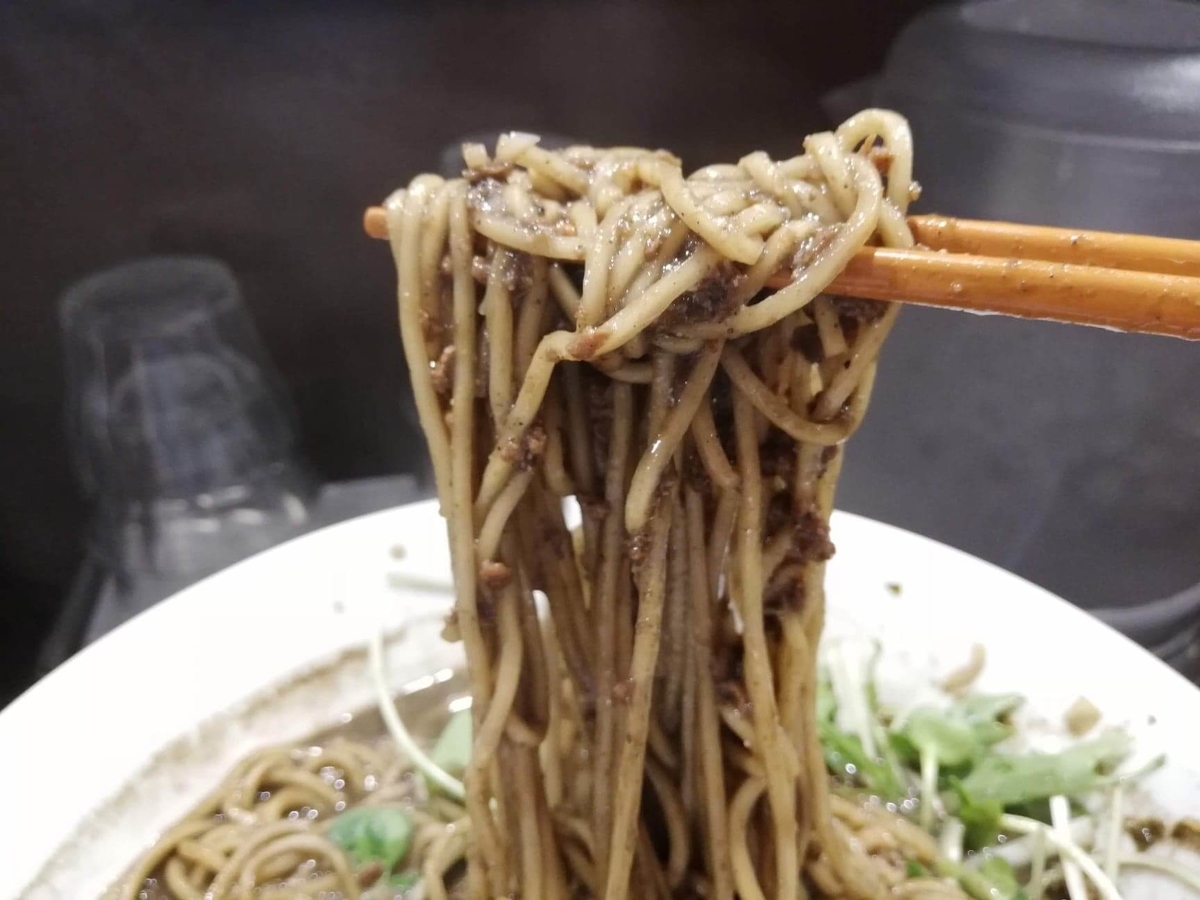 北浦和『四川担々麺（担担麺）阿吽』の黒胡麻担担麺を箸で掴んでいる写真