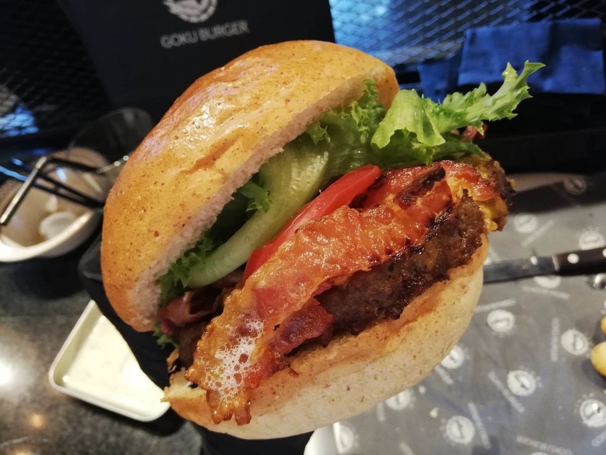 表参道『いしがまや GOKU BURGER(ゴクバーガー)』のBLTチーズバーガーを手で持ち上げた写真