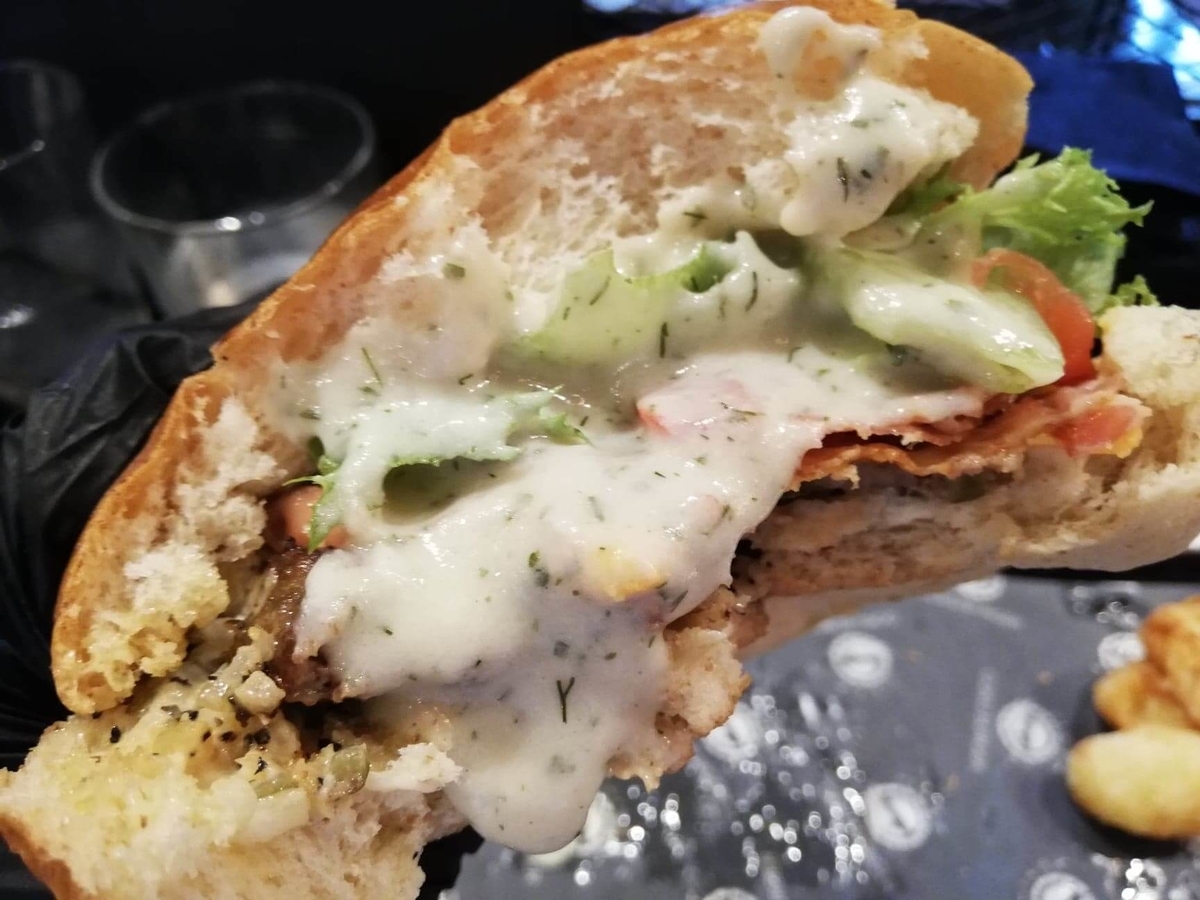 表参道『いしがまや GOKU BURGER(ゴクバーガー)』のBLTチーズバーガーにソースをかけた写真