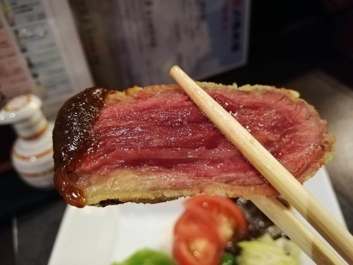 長野県松本市さくら料亭（馬肉料理）『新三よし』の、霜降り味噌カツを箸で掴んでいる写真