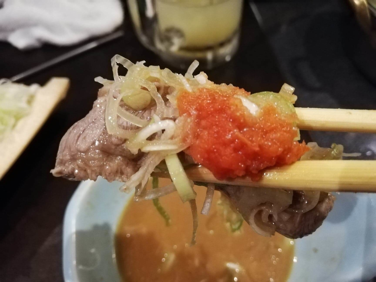 長野県松本市さくら料亭（馬肉料理）『新三よし』の、胡麻味噌だれしゃぶしゃぶ鍋の具材を箸で持ち上げている写真