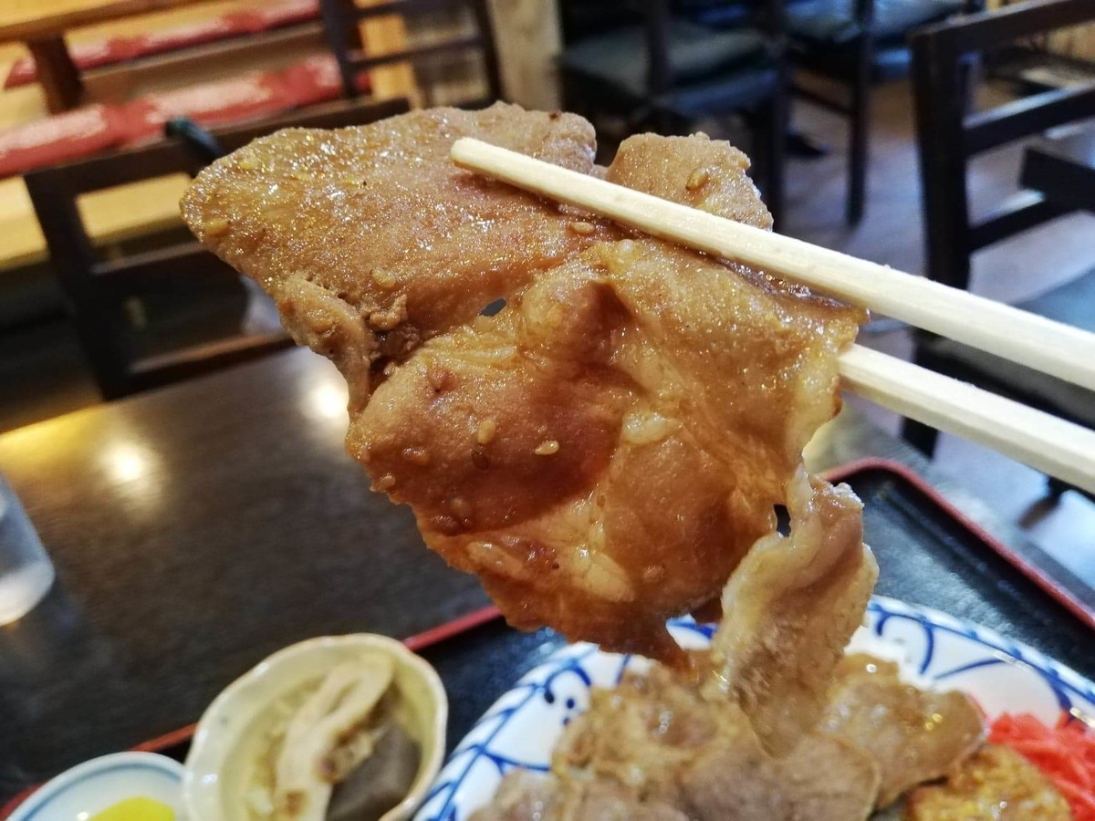 東池袋『伊東食堂』の焼肉を箸で掴んでいる写真