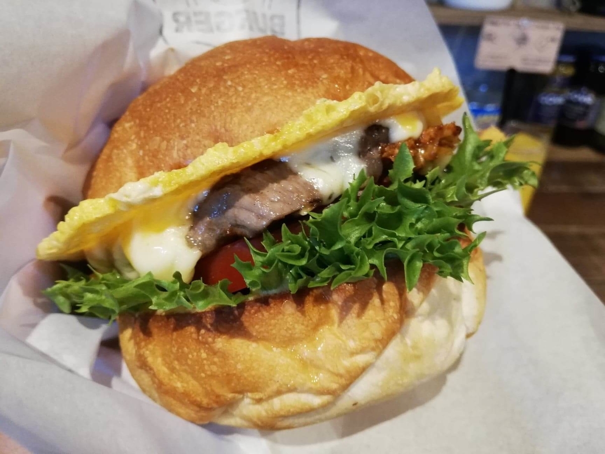 池袋『ビバラバーガー ( Viva la Burger ) 』の、ボウシ ( BOUSHI ) チーズバーガーを持ち上げた写真