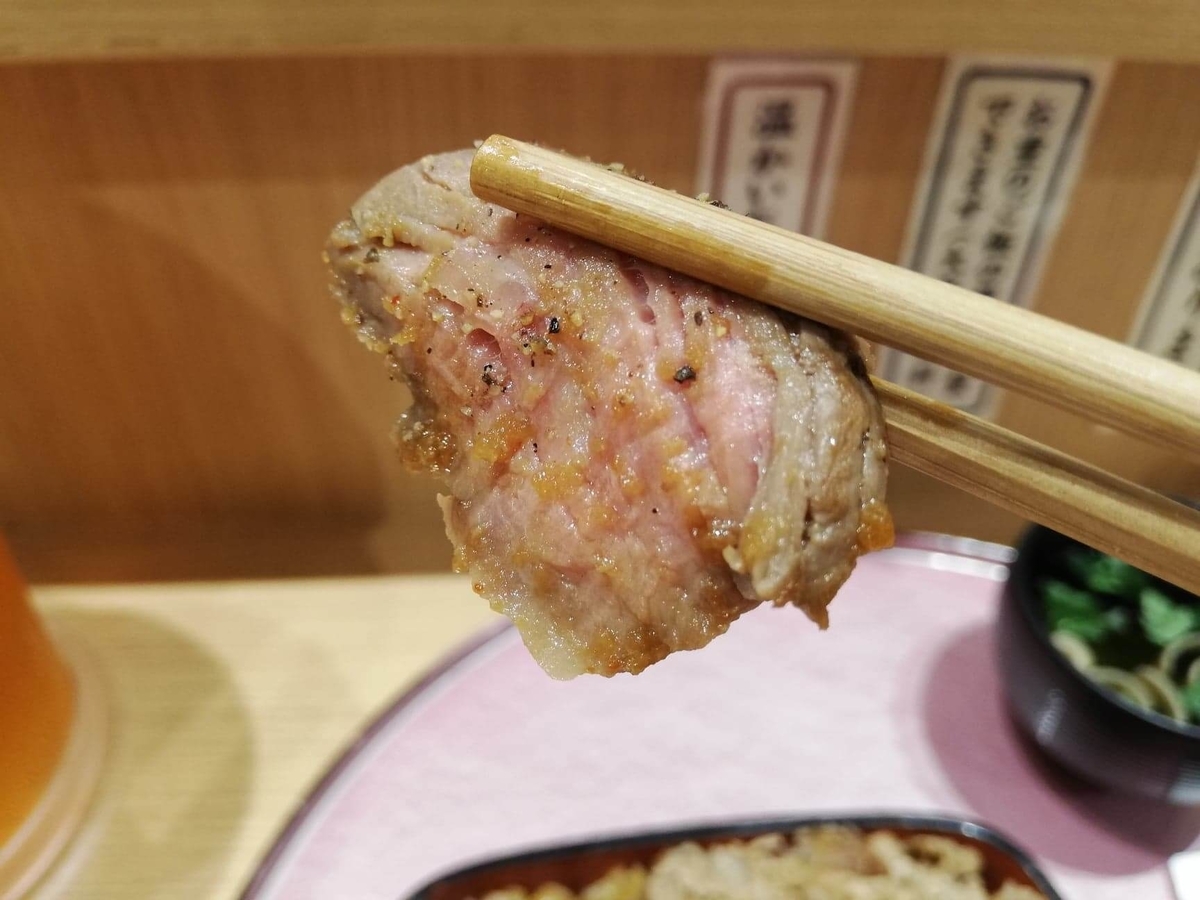 大阪『ビフテキ重・肉飯 ロマン亭』の、ビフテキを箸で掴んでいる写真